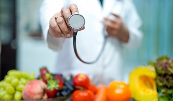 medico-nutricionista-sosteniendo-naranja-varias-frutas-verduras_39768-226